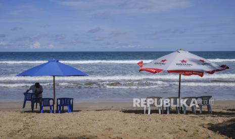 Seorang pria menata kursi di sebuah pantai di Kuta, Bali.