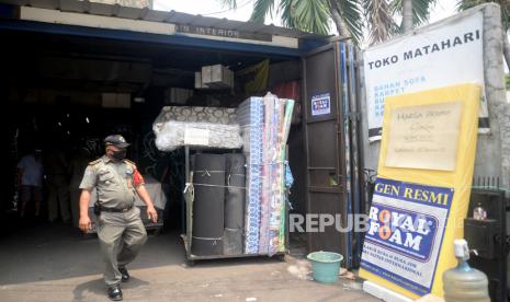 Petugas Satpol PP saat melakukan pengawasan PSBB di salah satu tempat usaha di Kawasan Jatinegara, Jakarta, Selasa (15/9). Pengawasan tersebut dilakukan untuk memastikan masyarakat untuk mematuhi dan tertib aturan yang berlaku selama PSBB di DKI Jakarta.Prayogi/Republika. 