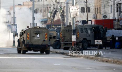 Seorang tentara Israel berlindung di balik kendaraan militer melintas kamp pengungsi Askar, di pinggir Kota Nablus, Tepi Barat. 