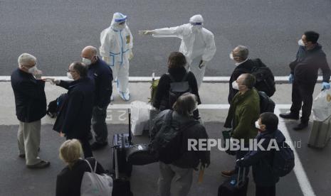  Seorang pekerja dengan penutup pelindung mengarahkan anggota tim Organisasi Kesehatan Dunia (WHO) pada saat kedatangan mereka di bandara di Wuhan di provinsi Hubei China tengah pada Kamis, 14 Januari 2021. Sebuah tim peneliti global tiba Kamis di kota China di mana pandemi virus korona pertama kali terdeteksi untuk melakukan penyelidikan yang sensitif secara politik tentang asal-usulnya di tengah ketidakpastian tentang apakah Beijing mungkin mencoba mencegah penemuan yang memalukan.