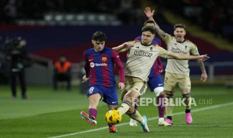 Pedri (kiri) dari FC Barcelona beraksi melawan Miguel Rubio (tengah) dari Granada selama pertandingan sepak bola LaLiga EA Sports Spanyol antara FC Barcelona dan Granada di stadion Lluis Companys di Barcelona, Spanyol, Senin (12/2/2024) dini hari WIB. 