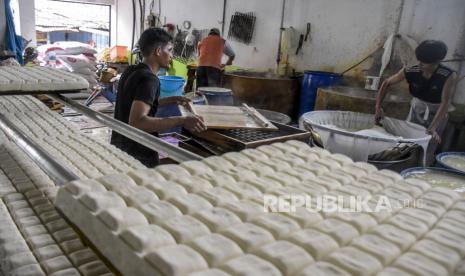 Pekerja menyelesaikan pembuatan tahu di salah satu pabrik di Sentra Industri Tahu Cibuntu, Babakan Ciparay, Kota Bandung, Kamis (24/2/2022). Seluruh Industri Perajin Tahu di kawasan tersebut kembali berproduksi setelah melakukan mogok produksi selama tiga hari imbas melonjaknya harga kacang kedelai sebagai dasar pembuatan tahu. Saat ini, para perajin menaikkan harga tahu menjadi Rp55 ribu per papan yang semula Rp50 ribu. Foto: Republika/Abdan Syakura