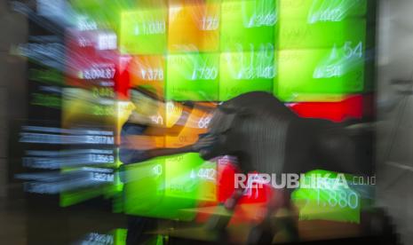 Pekerja membersihkan patung banteng dengan latar belakang layar pergerakan Indeks Harga Saham Gabungan (IHSG). IHSG berpeluang menguat seiring kepastian tapering off oleh The Fed.