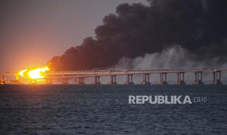 Api dan asap membubung dari Jembatan Krimea yang menghubungkan daratan Rusia dan semenanjung Krimea di atas Selat Kerch, di Kerch, Krimea, 8 Oktober 2022. Pihak berwenang Rusia mengatakan sebuah bom truk telah menyebabkan kebakaran dan runtuhnya sebagian jembatan menghubungkan Krimea yang dicaplok Rusia dengan Rusia. Tiga orang telah tewas. Jembatan itu adalah arteri pasokan utama bagi upaya perang Moskow yang goyah di Ukraina selatan.