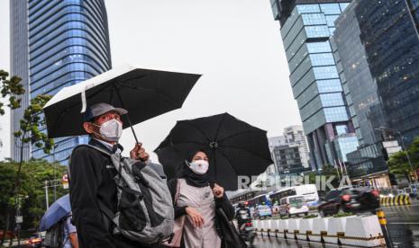 Sejumlah warga menggunakan payung saat hujan di kawasan Jalan Jenderal Sudirman, Jakarta.