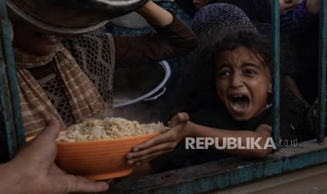 Anak-anak berdiri di pertemuan pengungsi Palestina untuk mengumpulkan makanan, di kamp Khan Yunis, Jalur Gaza selatan, 15 Juni 2024. Kantor UNRWA kini diratakan oleh Israel.