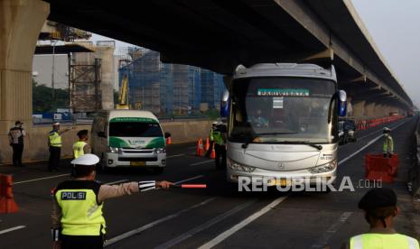 Petugas gabungan mengarahkan kendaraan untuk keluar Tol Cikarang Barat, di ruas Tol Cikampek, Jabar,Ahad (26/042020). Larangan mudik dan sosialisasi aturan Pembatasan Sosial Berskala Besar (PSBB) di ruas tol itu guna mencegah penyebaran COVID-19 dengan membatasi kendaraan pribadi dan angkutan umum yang melintas