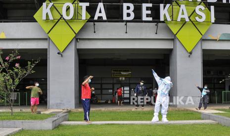 Petugas medis (kedua kanan) menggunakan Alat Pelindung Diri (APD) bersama pasien COVID-19 yang berstatus OTG (Orang Tanpa Gejala) saat kegiatan senam pagi di Stadion Patriot Chandrabhaga, Bekasi, Jawa Barat, Rabu (16/12/2020). Kegiatan senam tersebut rutin dilakukan setiap pagi hari untuk meningkatkan daya tahan tubuh pasien yang menjalani isolasi. 