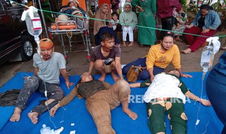  Orang-orang yang terluka saat gempa menerima perawatan medis di tempat parkir rumah sakit di Cianjur, Jawa Barat, Senin, 21 November 2022. Gempa bumi yang mengguncang pulau utama Indonesia di Jawa pada hari Senin merusak puluhan bangunan dan mengirim penduduk ke jalan-jalan ibu kota untuk keamanan.