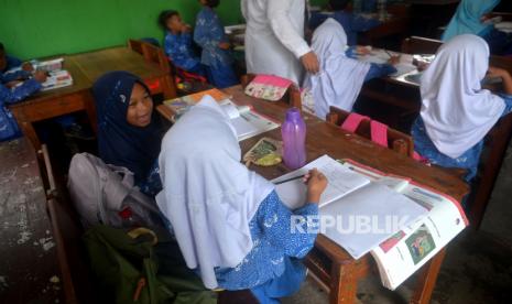 Siswa kelas 1 SD Negeri 3 Bantul mengikuti belajar di parkiran yang menjadi kelas darurat, Yogyakarta, Rabu (16/11/2022). Kegiatan belajar harus dipindah karena kelas 1a dan 1b rusak dan berpotensi roboh sewaktu-waktu. Kemampuan literasi siswa SD menurun sejak pandemi Covid-19.