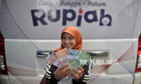 Warga menunjukan uang tunai baru usai menukarkannya di layanan kas keliling  Bank Indonesia di kawasan Pasar Tebet Barat, Jakarta, Selasa (28/3/2023).  Nilai tukar (kurs) rupiah yang ditransaksikan antarbank di Jakarta pada akhir pekan berpotensi menguat didukung aliran dana investor masuk ke surat berharga negara (SBN).