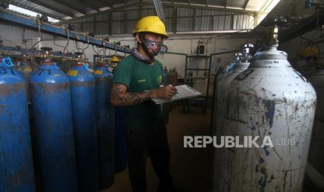 Seorang pekerja mencatat nomor seri tabung oksigen yang telah diisi di pabrik oksigen. 