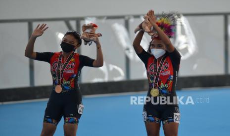 Atlet sepatu roda putri Papua Deitalianis Stugriam (kanan) dan Zhahwa Harmalia Putri (kiri) menyapa penonton usai upacara pengalungan medali pada final 400 meter individual time trial (ITT) putri PON Papua di Arena Klemen Tinal Roller Sport, Kota Jayapura, Papua, Senin (27/9/2021). Atlet sepatu roda Papua Deitalianis Stugriam berhasil meraih medali emas dengan catatan waktu 35,367 detik sementara medali perak diraih atlet sepatu roda DKI Jakarta Latisha Luna Sasmito (35,435 detik) dan medali perunggu disabet Zhahwa Harmalia Putri asal Papua (35,460 detik). 