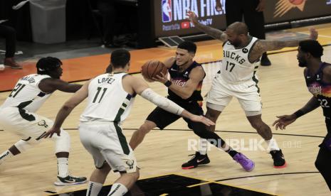  Guard Phoenix Suns Devin Booker (2-kanan) beraksi antara Milwaukee Bucks (kiri) Jrue Holiday, Brook Lop dan PJ Tucker di paruh kedua game dua seri playoff bola basket Final NBA 2021 antara Milwaukee Bucks dan Phoenix Suns the di Phoenix Suns Arena di Phoenix, Arizona, AS, 9 Juli 2021.