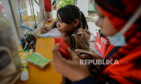 Siswi kelas 2 SDN 01 Pagi Bukit Duri Keysha belajar daring ditemani ibunya Okta (31) di gerai makanan tempat Ibunya kerja di kawasan Bukit Duri, Jakarta, Rabu (29/7). Pembelajaran Jarak Jauh (PJJ) dengan menggunakan metode daring dan bimbingan orang tua masih menjadi kendala, menurut Okta selain harus mencari nafkah untuk keluarganya Ia harus tetap membimbing anaknya belajar di tempatnya bekerja.