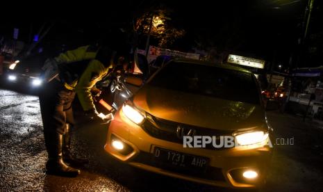 Petugas kepolisian memeriksa identitas dan surat keterangan Covid-19 pengendara dengan pelat nomor dari luar Garut. (ilustrasi)