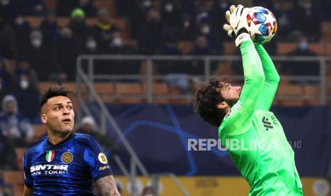 Penjaga gawang Liverpool Alisson Becker (kanan) menghalau bola dari Lautaro Martinez (tengah) Inter pada pertandingan leg pertama babak 16 besar Liga Champions UEFA antara Inter Milan dan Liverpool FC di Milan, Italia, Rabu (16/2/2022).