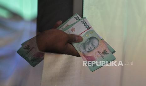 Petugas memberikan uang kepada warga yang melakukan penukaran uang rupiah.