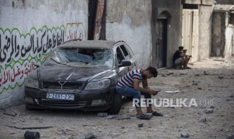 Seorang pria Palestina duduk di mobil yang rusak setelah serangan udara Israel di kamp pengungsi Jabaliya, Jalur Gaza utara, Kamis, 20 Mei 2021. 