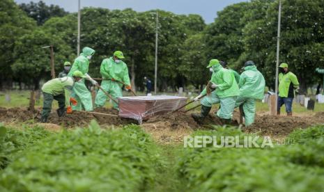 Petugas memasukan peti jenazah pasien suspect Corona ke liang lahat di Tempat Pemakaman Umum (TPU)