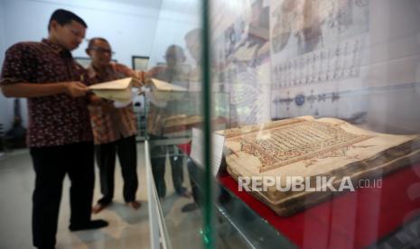 Pengunjung melihat naskah kuno manuskrip koleksi sejarawan Aceh Tarmizi Abdul Hamid  (kanan) di Desa Pineung, Banda Aceh, Aceh, Rabu (30/3/2022). Tarmizi Abdul Hamid memiliki koleksi 150 manuskrip Aceh yang telah dikonservasi Tim Pusat Preservasi Naskah Kuno dan Alih Media Perpustakaan Nasional untuk pemanfaatannya bagi keilmuan Nusantara. 