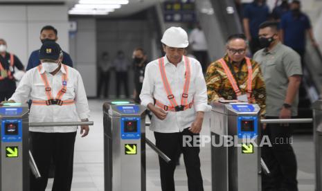 Presiden Joko Widodo (tengah) didampingi Menteri PUPR Basuki Hadimuljono (kiri) berjalan melintasi gerbang pembayaran di Stasiun Light Rail Transit (LRT) Taman Mini Indonesia Indah, Jakarta, Senin (26/12/2022). Presiden Joko Widodo berharap proyek LRT Jabodebek yang perkembangannya telah mencapai 85 persen itu bisa beroperasi dan digunakan masyarakat pada Juli 2023. 