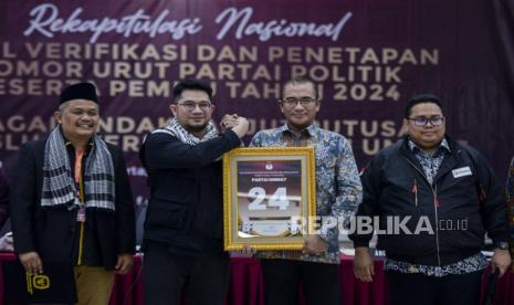 Ketua KPU Hasyim Asyari (kedua kanan) bersama Ketua Bawaslu Rahmat Bagja (kanan), Ketua Umum Partai Ummat Ridho Rahmadi (kedua kiri) dan Sekjen Partai Ummat Ahmad Muhajir Sodruddin saat menyerahkan plakat di Jakarta, Jumat (30/12/2022). KPU menetapkan Partai Ummat sebagai peserta Pemilu 2024 setelah berhasil memenuhi syarat keanggotaan dalam proses verifikasi faktual ulang di dua provinsi. Republika/Putra M. Akbar