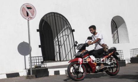 Pengendara sepeda motor yang tak mengenakan masker melintas di kawasan bangunan cagar budaya Panggung Krapyak, Sewon, Bantul, DI Yogyakarta, Kamis (23/7/2020). Pemerintah Kabupaten Bantul menerapkan sanksi berupa denda sebesar Rp100 ribu bagi warga yang keluar di tempat umum tanpa menggunakan masker. 