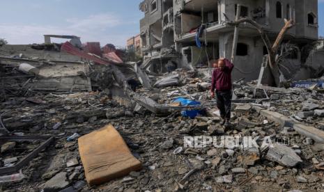 Palestinians inspect the rubble of a building of the Al Nawasrah family destroyed in an Israeli strike in Maghazi refugee camp, central Gaza Strip, Monday, Dec. 25, 2023. 