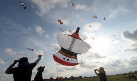 Sejumlah peserta berusaha menurunkan layang-layang saat mengikuti perlombaan dalam Dwi Tunggal Melesat Kite Festival di persawahan Nyalin, Desa Pedungan, Denpasar, Bali, Sabtu (4/6/2022). Kegiatan yang digelar untuk pelestarian permainan tradisional Bali tersebut kembali diselenggarakan setelah sempat ditiadakan selama dua tahun akibat pandemi COVID-19. 