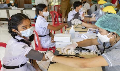 Siswa sekolah menjalani pemeriksaan kesehatan selama vaksinasi massal COVID-19 untuk remaja. 