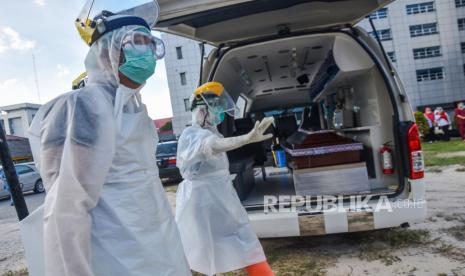 Sejumlah tenaga kesehatan mengenakan alat pelindung diri lengkap untuk memasukan peti mati berisi jenazah pegawai Rumah Sakit Umum Daerah (RSUD) Arifin Achmad, yang wafat akibat terpapar COVID-19, saat pelepasan jenazah di Kota Pekanbaru, Riau, Selasa (22/9/2020). Pemerintah Indonesia terus berusaha menekan angka kematian pasien COVID-19, karena hingga 22 September sudah ada 9.837 pasien meninggal dari total 252.923 kasus terkonfirmasi COVID-19 di Tanah Air secara akumulatif. 