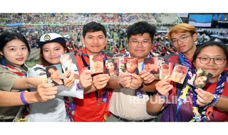 Pramuka berpose untuk foto sambil memamerkan kartu foto BTS.