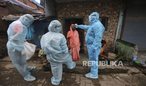 Seorang pekerja kesehatan India yang mengenakan alat pelindung diri memeriksa suhu seorang wanita selama kamp pemeriksaan di sebuah perkampungan kumuh di Mumbai, India, Rabu, 17 Juni 2020. 