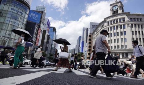 Orang-orang yang memakai masker wajah untuk membantu melindungi dari penyebaran virus corona berjalan di bawah terik matahari di distrik Perbelanjaan Ginza Selasa, 10 Agustus 2021, di Tokyo.