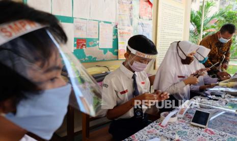 Siswa membuat pelindung wajah (face shield) dengan dibantu guru di halaman SMP Negeri 13 Solo, Jawa Tengah, Jumat (12/6/2020). Sekolah setempat memberikan bahan untuk membuat pelindung wajah bagi para siswa sebagai persiapan pelaksanaan Kegiatan Belajar Mengajar (KBM) menjelang tahun ajaran baru 2020/2021 yang disesuaikan dengan protokol penanganan pandemi COVID-19, jika Solo menerapkan situasi normal