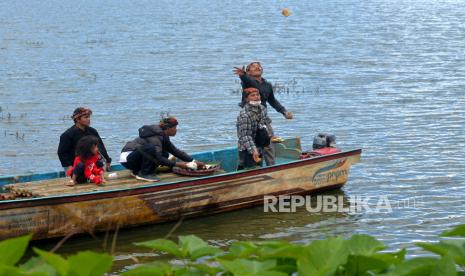 Pantia melempar hasil bumi saat pelarungan ritual ruwat cukur rambut gimbal di Telaga Cebong, Sembungan, Dieng, Wonosobo, Jawa Tengah, Ahad (3/7/2022). Ritual cukur rambut gimbal kembali diadakan usai absen selama dua tahun imbas pandemi Covid-19. Dalam tradisi ini selain anak-anak, terkadang orang dewasa juga mengikuti potong rambut gimbal. Namun, warga yang ikut harus kehendak sendiri dan nanti akan meminta permintaan khusus. Tanpa ada ritual atau ruwat ini warga yang memiliki rambut gimbal akan terus ada meski sudah dipotong berkali-kali.