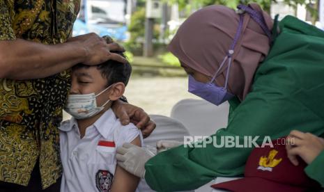 Vaksinator menyuntikkan vaksin Covid-19 ke siswa Sekolah Dasar (SD).