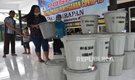 Warga mengambil ember kran yang dibagikan di Desa Sirapan, Kabupaten Madiun, Jawa Timur, Jumat (27/3/2020). Desa setempat mengalokasikan Dana Desa untuk pengadaan 350 buah ember kran dan sabun untuk cuci tangan yang dibagikan untuk ditempatkan di lokasi kerumunan masyarakat, seperti warung, pos Kamling, masjid dan mushala guna pencegahan penyebaran COVID-19 atau virus Corona