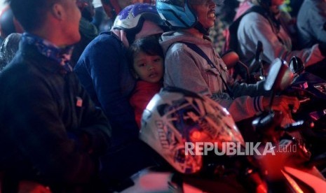 Pemudik sepeda motor yang membawa anaknya mengantri memasuki kapal di Pelabuhan Merak ,Banten, Selasa (12/6) dini hari.