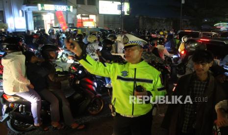 Polisi lalu lintas berupaya mengatur lalu lintas di kawasan Jalan Asia Afrika, Kota Bandung, saat malam pergantian tahun baru 2024, Ahad (31/12/2023). Kawasan Jalan Braga, Asia Afrika dan Alun-alun, menjadi pusat titik kumpul warga saat merayakan malam Tahun Baru. Meski pusat kota dikepung macet, perayaan Tahun Baru di Kota Bandung berlangsung kondusif.