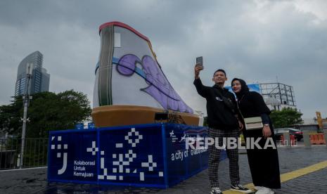 Warga berswafoto di area Tugu Sepatu di kawasan Stasiun BNI City, Jakarta, Ahad (19/9). Tugu Sepatu yang baru diresmikan pada Jumat (17/9) kemarin ini menjadi sasaran vandalisme sejumlah oknum. Akibat aksi tersebut Pemprov DKI Jakarta akan segera menindak lanjuti aksi vandal tersebut. Republika/Thoudy Badai