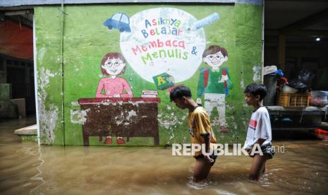 Anak-anak berjalan melintasi banjir yang melanda kawasan Kebon Pala, Kampung Melayu, Jakarta, Kamis (30/1/2025). Banjir akibat luapan Kali Ciliwung  tersebut menggenangi rumah warga dengan ketinggian 50-150 cm. Banjir ini merupakan yang kedua kalinya karena pada Rabu (29/1/2025) kawasan ini juga terendam banjir. Meski sudah dua hari berturut-turut terendam banjir luapan Kali Ciliwung,hingga Kamis siang belum ada warga yang mengungsi. Mereka memilih bertahan di lantai dua rumahnya masing-masing, dan hanya memindahkan perabot serta kendaraan sepeda motor ke tempat lebih tinggi agar tidak terendam.