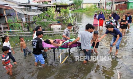 Petugas medis dibantu warga mengevakuasi seorang warga yang sakit saat terjadi banjir di Aceh 