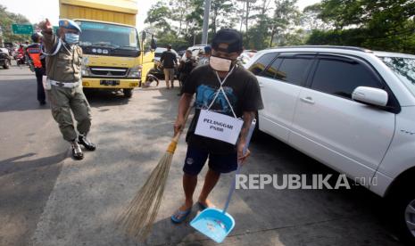 Petugas Satpol PP memberikan sanksi sosial kepada warga yang tidak memakai masker untuk menyapu jalan saat razia di simpang Ciawi, Kabupaten Bogor, Jawa Barat, Kamis (10/9/2020). Razia gabungan Kota dan Kabupaten Bogor bersama TNI-Polri serta Satpol PP tersebut guna mendisiplinkan warga untuk patuh terhadap protokol kesehatan pencegahan penularan COVID-19. 