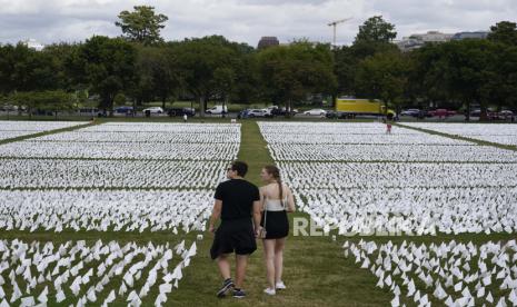  Orang-orang mengunjungi In America: Remember karya seniman Suzanne Brennan Firstenberg, sebuah instalasi seni sementara yang terbuat dari bendera putih untuk memperingati orang Amerika yang telah meninggal karena Covid-19, di National Mall di Washington, Selasa, 21 September 2021. Usia harapan hidup pria di AS turun di tengah pandemi Covid-19.