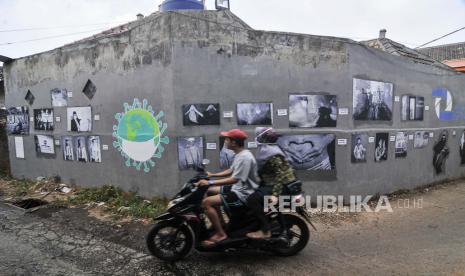 Pengendara motor melintasi foto yang dipamerkan di ruang publik daerah Jati Asih, Bekasi, Jawa Barat, Rabu (8/7/2020). Pameran yang diadakan Komunitas Fotografi Zepret STIKOM Inter Studi menampilkan 23 karya foto untuk mengedukasi warga untuk menjaga kebersihan saat masa pandemi COVID-19. 