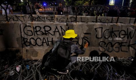 Massa dari Aliansi BEM SI menuliskan pesan aksi di tembok pembatas saat aksi Geruduk Istana di kawasan Patung Kuda, Jakarta, Jumat (20/10/2023). Aksi tersebut merupakan respon atas putusan Mahkamah Konstitusi yang dinilai dapat melanggengkan praktik KKN dan politik dinasti. Aksi tersebut berlangsung hingga malam hari, massa aksi membubarkan diri sekitar pukul 20.00 WIB.