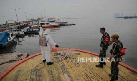 Petugas Dit Polair menyemprotkan cairan disinfektan di kapal penumpang di Pelabuhan Kaliadem, Muara Angke Jakarta, Jumat (19/6). Penyemprotan dilakukan di area pelabuhan dan kapal-kapal saat penerapan PSBB transisi setelah dibuka kembali jalur penyeberangan ke pulau seribu guna mengantisipasi penyebaran COVID-19 di kawasan tersebut