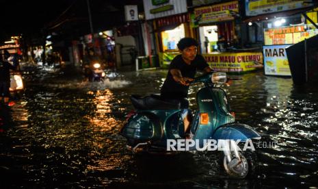 Warga mendorong motornya yang mogok akibat melintasi jalan yang tergenang banjir di Ciwastra, Bandung, Jawa Barat, Jumat (7/3/2025). Sejumlah wilayah di Kota Bandung tergenang banjir setinggi 30 - 50 sentimeter akibat diguyur hujan deras pada Jumat petang hingga malam hari. 